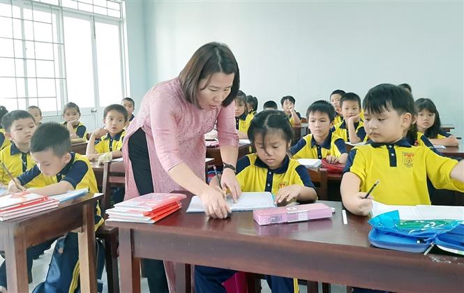 Giáo viên trường Tiểu học Âu Cơ, thành phố Tuy Hòa (Phú Yên), hướng dẫn học sinh viết chữ. Ảnh: Xuân Triệu/TTXVN